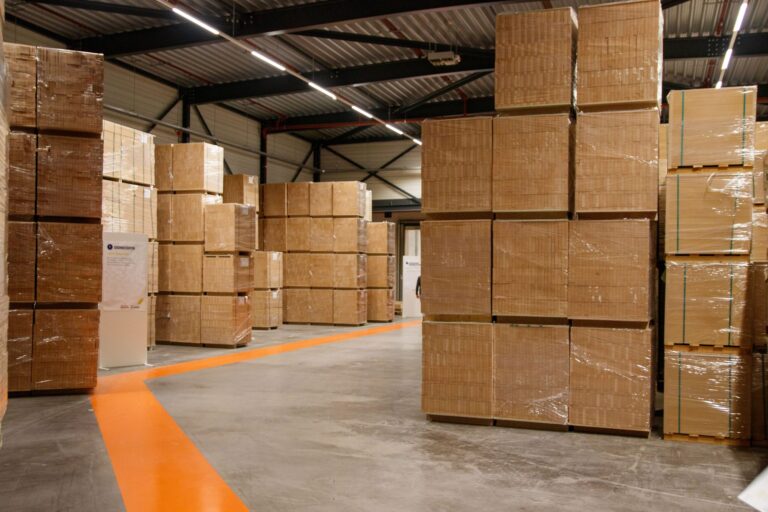 Opslagloods met gestapelde pallets onder doorlopende lichtlijnen